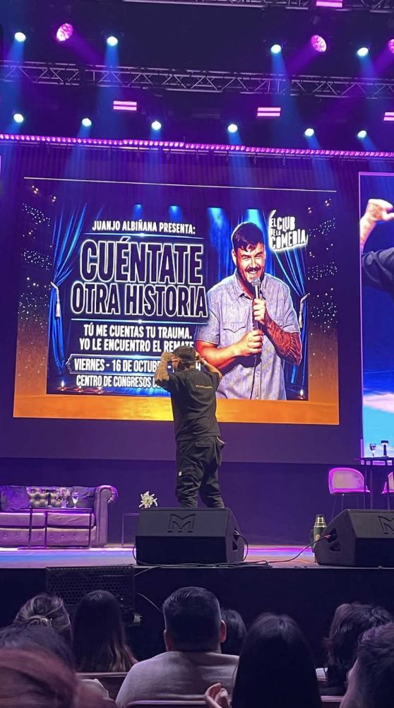 Juanjo en el escenario con el cartel proyectado detrás